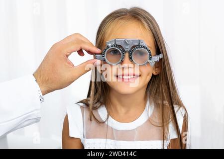 Medico in possesso di un'attrezzatura speciale per gli occhi della ragazza Foto Stock
