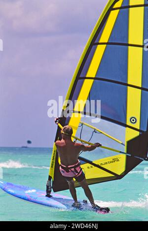 Uomo in vacanza che gode di condizioni meteorologiche perfette per il windsurf (vela da diporto) in acque cristalline al largo di Aruba, California. primi anni '1990 Si prega di accreditare il fotografo: Joan Iaconetti Foto Stock