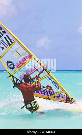 Uomo in vacanza che gode di condizioni meteorologiche perfette per il windsurf (vela da diporto) in acque cristalline al largo di Aruba, California. primi anni '1990 Si prega di accreditare il fotografo: Joan Iaconetti Foto Stock