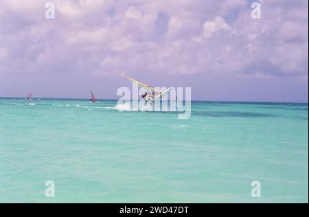 Un giovane vola fuori dall'acqua mentre fa windsurf (vela da diporto) nelle acque al largo di Aruba, California. primi anni '1990 Si prega di accreditare il fotografo: Joan Iaconetti Foto Stock