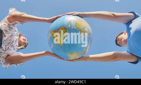 Una ragazza e un ragazzo girano un globo del mondo. Il concetto di pace e creazione. Foto Stock