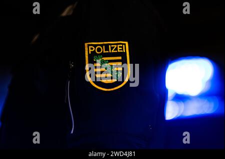 Dresda, Germania. 18 gennaio 2024. Un poliziotto sta accanto a un'auto della polizia. Credito: Robert Michael/dpa/Alamy Live News Foto Stock