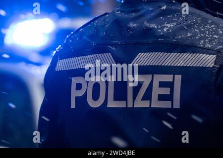 Dresda, Germania. 18 gennaio 2024. Un poliziotto sta accanto a un'auto della polizia. Credito: Robert Michael/dpa/Alamy Live News Foto Stock