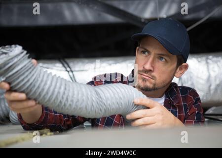 Tecnico di impianti di termoventilazione pronto per installare il sistema di ventilazione in casa Foto Stock