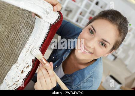 donna che dipinge una sedia a casa Foto Stock