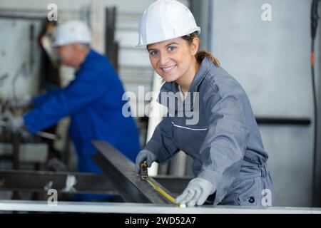 L uomo e la donna per misurare la lunghezza di metallo in officina Foto Stock