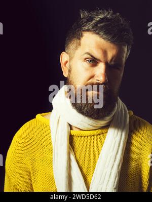 Splendido uomo con barba in maglione invernale giallo casual e sciarpa bianca lavorata a maglia. Abbigliamento autunno-inverno. Moda maschile. Ritratto in primo piano di attraente Foto Stock