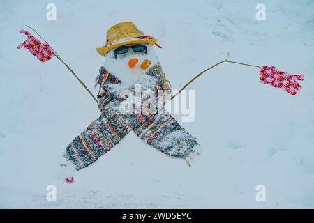 Pupazzo di neve insolito con cappello, sciarpa, guanti, occhiali da sole Foto Stock