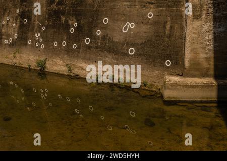 Fori di proiettile nel muro di cemento della guerra di Corea riflessi nell'acqua del torrente, Corea del Sud, Corea del Sud Foto Stock