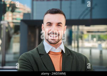 Vista frontale di un giovane adulto con un'espressione amichevole e positiva. Ritratto ravvicinato di un bel ragazzo barbuto con denti bianchi perfetti che sorridono e guardano la fotocamera all'aperto. Maschio felice. Foto di alta qualità Foto Stock