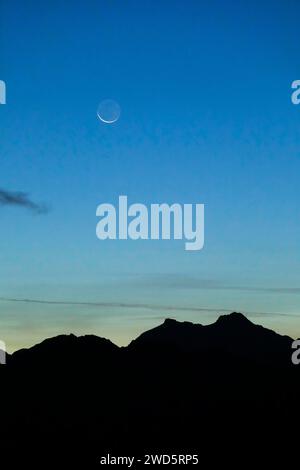 Luna a mezzaluna sulla silhouette di montagna, Vallese, Alpi svizzere Foto Stock