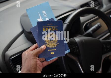 Mano che tiene il passaporto brasiliano in primo piano, simboleggia il viaggio e l'identità nazionale. Foto Stock