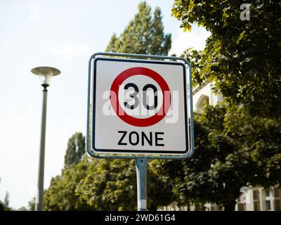 30 segnale del limite di velocità della zona in Germania. Il cartello stradale si trova in un quartiere residenziale per rallentare i conducenti per motivi di sicurezza. Foto Stock