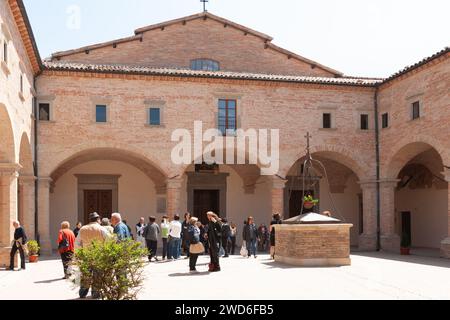 Gubio Umbria, Italia, 12 maggio 2011; il vecchio pozzo sormontato e i turisti nel cortile della basilica medievale di Sant'Ubaldo. Foto Stock