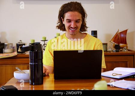 Giovane che lavora su un notebook da casa Foto Stock