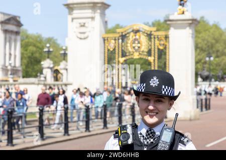 Una donna sorridente agente di polizia fuori Buckingham Palace, Londra Foto Stock
