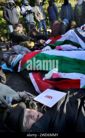 Gli attivisti si stendono sul terreno ghiacciato collegato l'uno all'altro con serrature di metallo, circondati da sostenitori nel mezzo della strada durante la demobazione. Palestine Action e i loro sostenitori bloccano l’unica porta di Elbit Systems. Hanno una campagna in corso per chiudere la compagnia di difesa israeliana Elbit Systems nel Regno Unito. Hanno chiuso con successo due dei loro dieci siti originali con un'azione diretta ripetitiva. Sostengono che la società produce droni che sono responsabili di molte morti Palestinianís a Gaza e altrove. Foto Stock