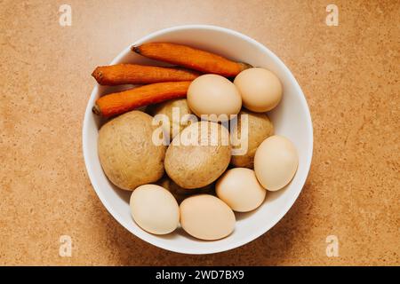 Ciotola piena di verdure bollite e uova su un tavolo in cucina. Vista dall'alto verso il basso. Foto Stock