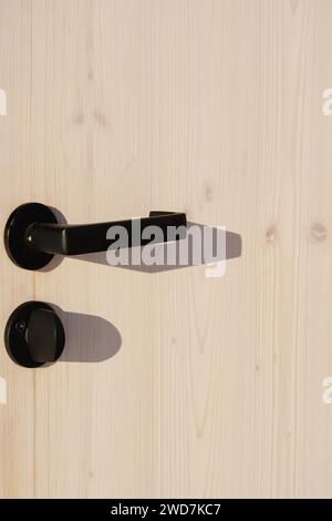 Maniglie delle portiere in legno e nere su una porta nera Foto Stock