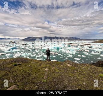 Uomo vicino alla laguna glaciale con iceberg e un bel cielo Foto Stock