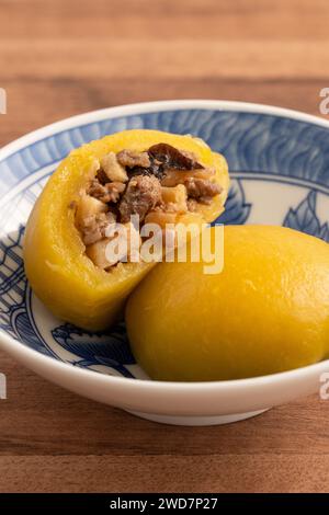 Panino di patate dolci fatto in casa con carne di maiale macinata, funghi e farciture di bambù tritate all'interno in una ciotola su fondo di legno. Foto Stock