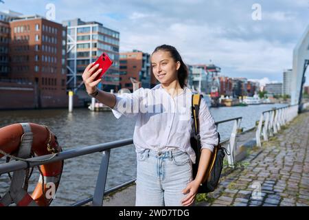 Giovane studentessa turista adolescente che scatta foto selfie su smartphone nella città portuale europea Foto Stock