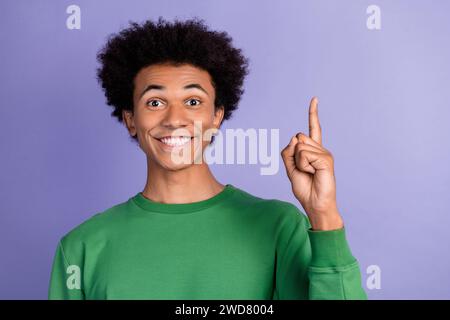 Foto di un ragazzo eccitato positivo che indossa un maglione verde puntato, spazio vuoto, sfondo viola isolato Foto Stock