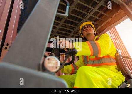 Conducente carrello elevatore uomo lavoratore personale che lavora carico carico container carico nel cantiere di spedizione logistica impiegato uomo di lavoro paese asiatico Foto Stock