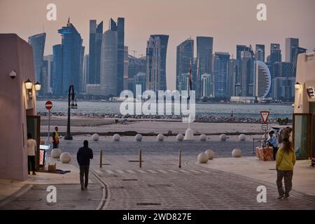 Il vecchio porto di Doha (Mina District) a Doha, Qatar, è stato girato nel pomeriggio mostrando lo skyline di Doha con gente del posto e visitatori che camminano Foto Stock
