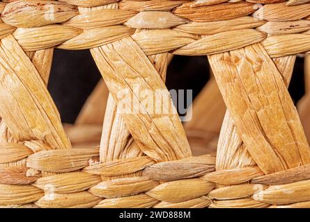 Primo piano di una trama di fondo di paglia intrecciata a mano, che mostra trame e motivi complessi. I toni naturali e terrosi creano un ambiente bello e rustico Foto Stock