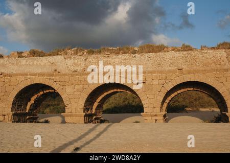 Archi in pietra e abutment dell'acquedotto Adriano del Parco Nazionale di Caesarea Maritima lungo la costa mediterranea di Israele al tramonto. Foto Stock