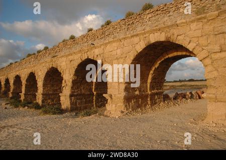 Archi in pietra e abutment dell'acquedotto Adriano del Parco Nazionale di Caesarea Maritima lungo la costa mediterranea di Israele al tramonto. Foto Stock