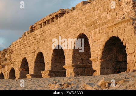 Archi in pietra e abutment dell'acquedotto Adriano del Parco Nazionale di Caesarea Maritima lungo la costa mediterranea di Israele al tramonto. Foto Stock