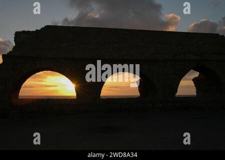 Archi in pietra e abutment dell'acquedotto Adriano del Parco Nazionale di Caesarea Maritima lungo la costa mediterranea di Israele al tramonto. Foto Stock