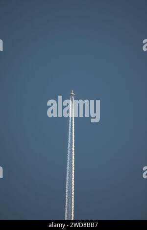 Foto di un aereo che vola verticalmente nel cielo azzurro, lasciando tracce di vapore nell'aria. Foto Stock