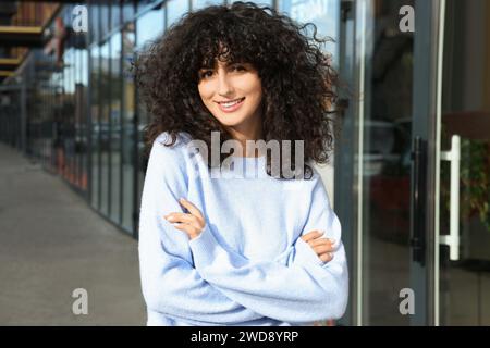 Giovane donna felice con un elegante maglione blu chiaro all'aperto Foto Stock