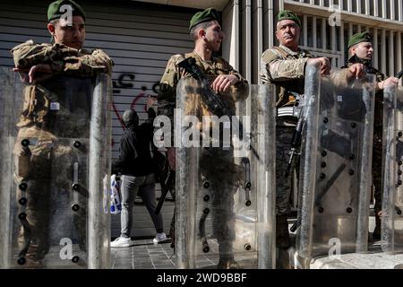 Beirut, Libano. 19 gennaio 2024. Il depositante libanese spruzza vernice sulla facciata di una banca locale assicurata dai soldati dell'esercito libanese, durante una protesta per chiedere l'imposizione di un calendario per restituire i risparmi dei depositanti. Le proteste dei depositanti contro le banche sono state espresse regolarmente dopo le restrizioni imposte dalle banche libanesi nel 2019, all’inizio di una crisi economica senza precedenti in cui il Libano è ancora coinvolto. Crediti: Marwan Naamani/dpa/Alamy Live News Foto Stock