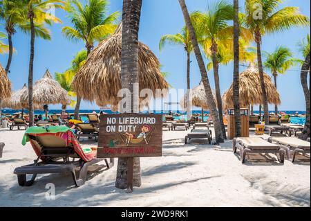 Tipica spiaggia caraibica, con un divertente cartello "No Lifeguard" inchiodato ad una palma Foto Stock