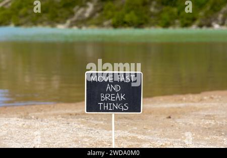 Muoviti in fretta e rompi il simbolo. Le parole concettuali si muovono velocemente e rompono le cose su una lavagna bellissima. Splendido sfondo di un lago di montagna. Affari, mov Foto Stock