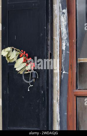 258 ghirlanda secca di holly -Ilex aquifolium- foglie verdi e bacche rosse, ornamento natalizio per porte e finestre, area del vecchio Bazaar. Korca-Albania. Foto Stock