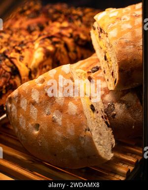 Il delizioso pane posto su ripiani in legno ha forme squisite e viene illuminato da luci calde. Foto Stock