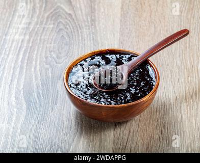 marmellata di blackberry in una ciotola di legno su un tavolo di legno Foto Stock