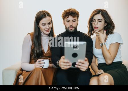 Tre giovani professionisti impegnati in una discussione collaborativa su un tablet digitale in un ambiente di ufficio moderno. Foto Stock