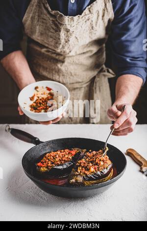 Preparazione delle melanzane farcite con carne macinata, pomodori e spezie. Piatto tradizionale Karniyarik di cucina turca Foto Stock