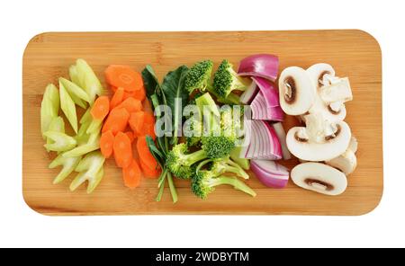 Verdure fresche a fette pronte per friggere su tagliere di bambù in formato orizzontale e composizione piatta. Concetto di cibo sano e nutriente. Foto Stock