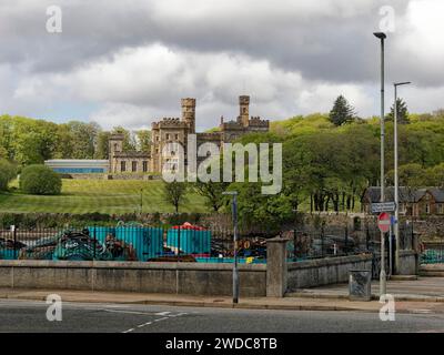 Castello storico dietro una recinzione su una collina circondata da alberi sotto un cielo nuvoloso, vista del castello di Lews a Stornoway. Isola di Harris e Lewis. Esterno Foto Stock