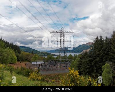 Una centrale elettrica nel mezzo di un paesaggio naturale con piloni elettrici e cielo nuvoloso, piloni ad alta tensione sul Loch Ness Scozia, Gran Bretagna Foto Stock