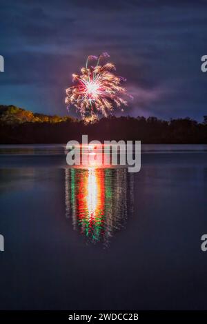 Fuochi d'artificio di notte di Capodanno sul lago Macquarie in Australia che si riflettono in acque ferme. Foto Stock