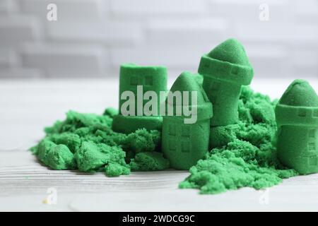 Figure del castello fatte di verde sabbia cinetica su un tavolo bianco, primo piano Foto Stock