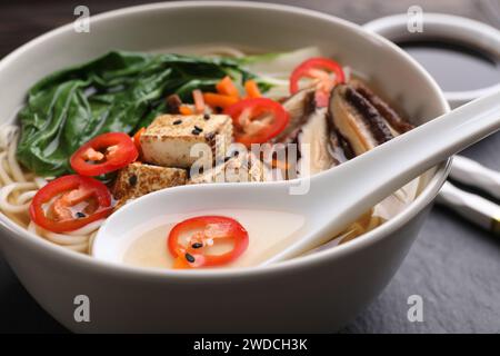 Ciotola di ramen vegetariano e cucchiaio sul tavolo, primo piano Foto Stock